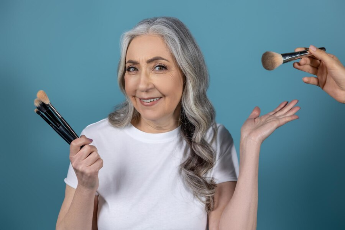 Beautiful senior woman holding makeup brushes